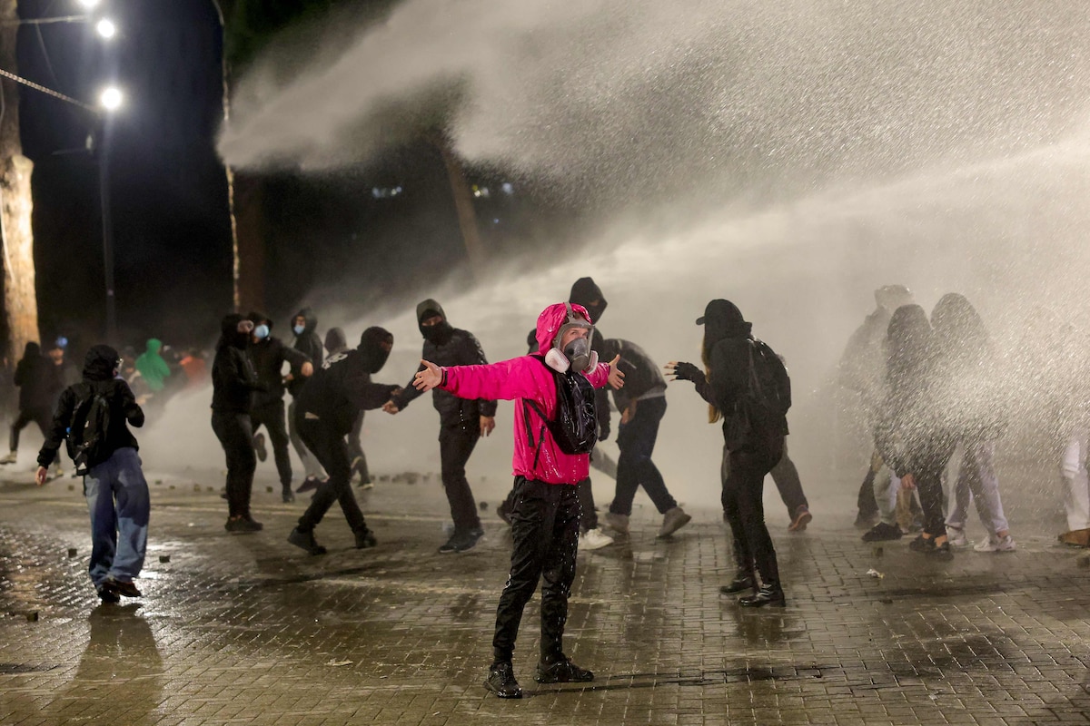Protesters gestures as they are sprayed by police water cannon during an anti-government demonstration in central Tirana on October 20, 2026, after a week of violent anti-government demonstrations. Albanian Prime Minister Edi Rama on October 20, 2026 blamed a "hybrid war" for fuelling unrest in his country, after a week of violent anti-government demonstrations demanding for better university conditions, anger over corruption and renewed calls for Prime Minister's resignation. (Photo by Adnan Beci / AFP)